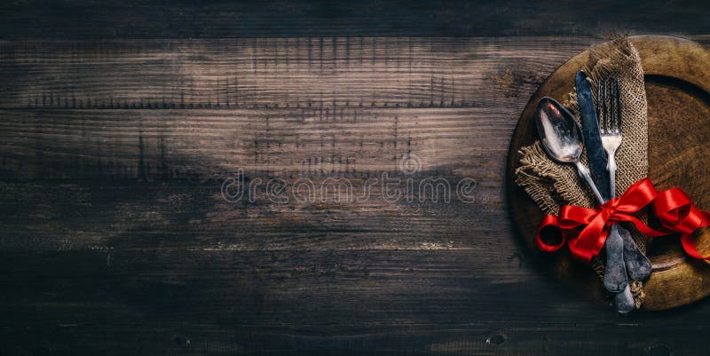 瓦伦特餐厅的晚餐配有复古银器餐盘和木桌上的红丝带. 情人节背景框 库存照片