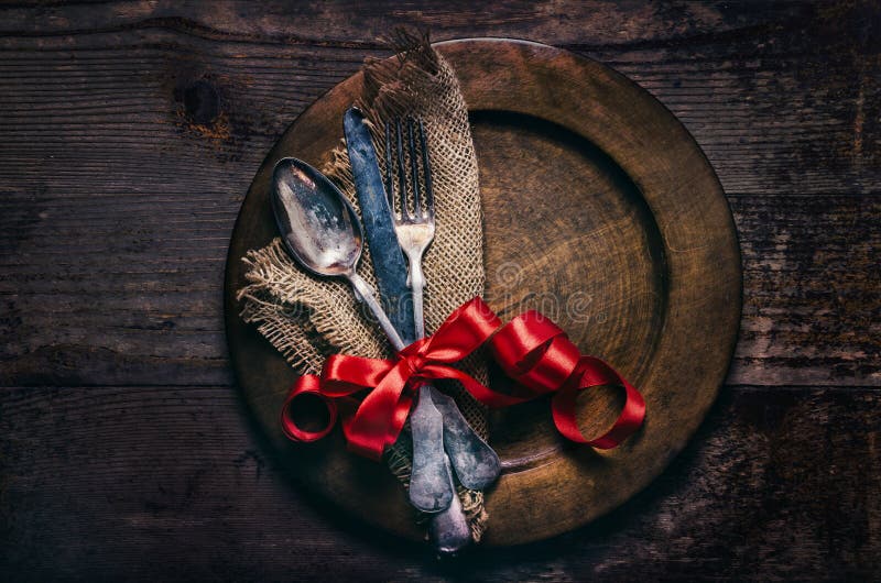 瓦伦特餐厅的晚餐配有复古银器餐盘和木桌上的红丝带. 情人节背景框 库存照片
