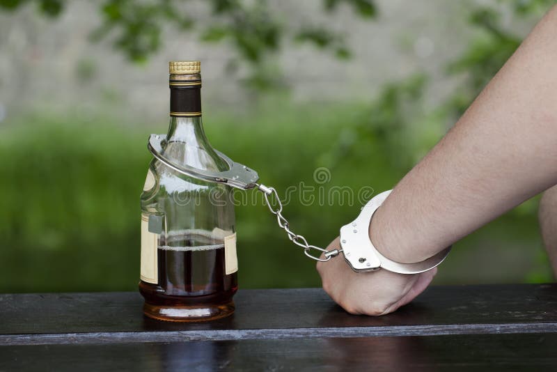 Man in handcuffs interconnected with a bottle of alcohol. Man in handcuffs interconnected with a bottle of alcohol