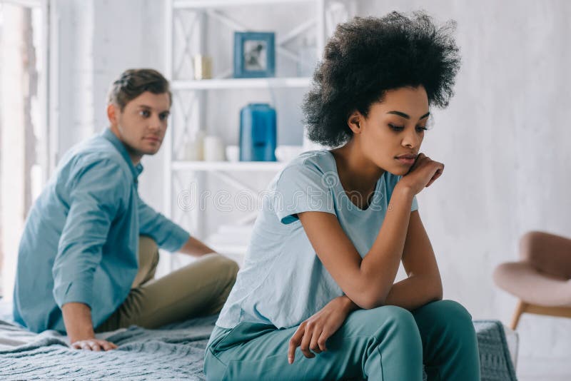 生氣非裔美國人的女孩坐床由她的男朋友 庫存照片 生氣非裔美國人的女孩坐床由她的男朋友 庫存照片
