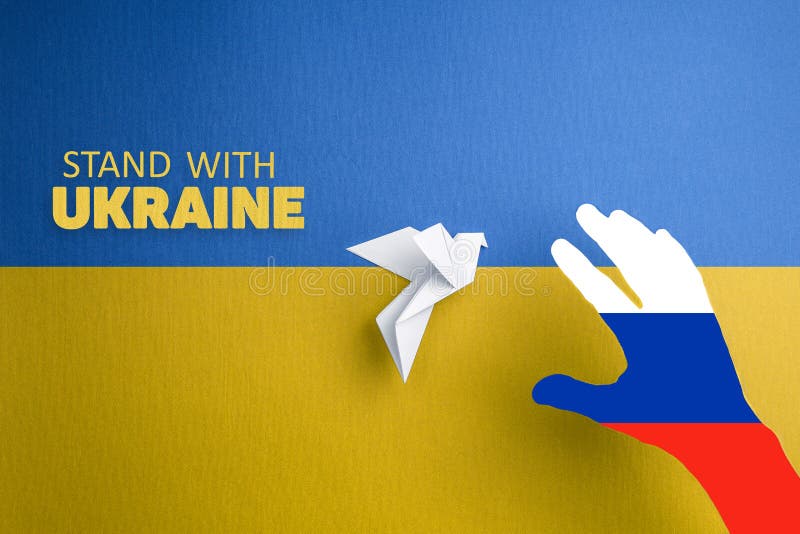 hand with colors of russian flag catches paper dove on yellow and blue background with words stand with Ukraine. terror and annexation. hand with colors of russian flag catches paper dove on yellow and blue background with words stand with Ukraine. terror and annexation