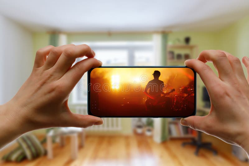在家通过智能手机观看在线音乐会。现场直播音乐视频 免版税库存照片