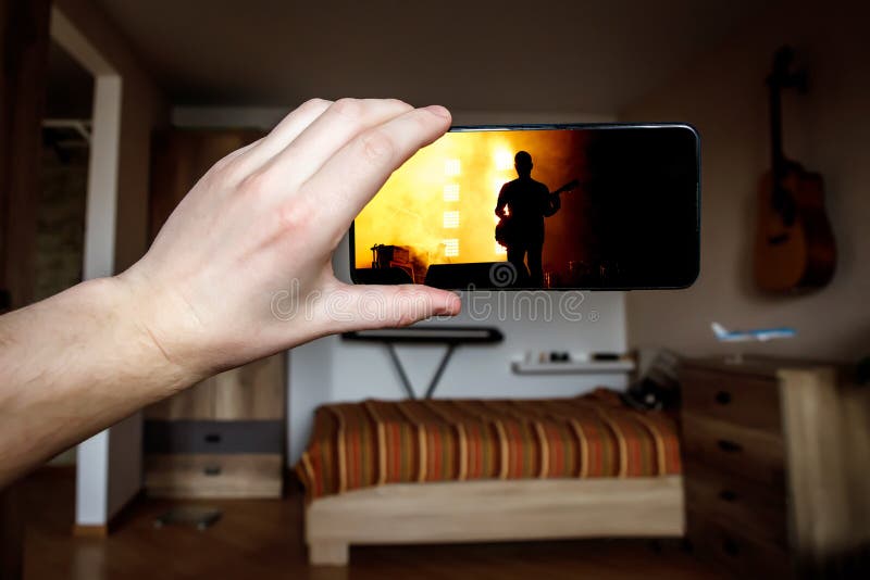 用智能手机在家观看网上音乐会 现场流音乐视频 图库摄影