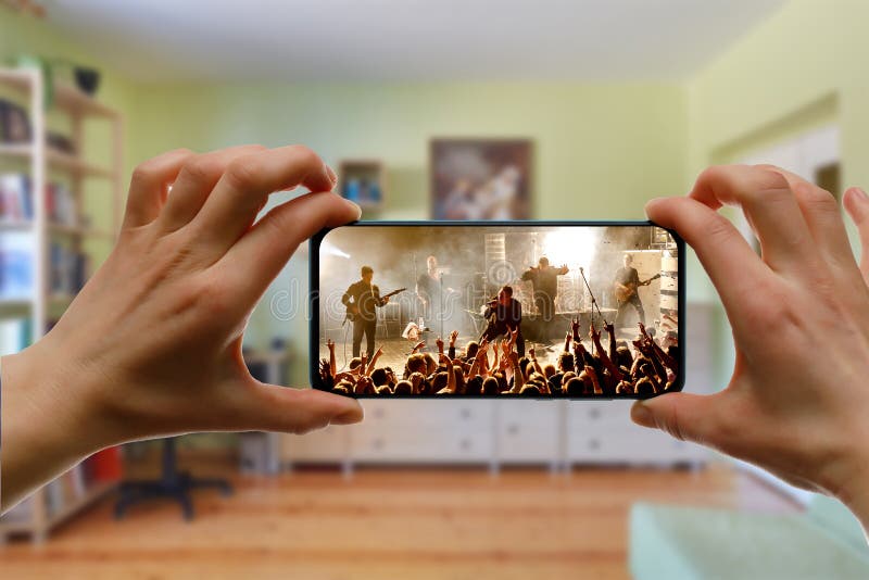 在家通过智能手机观看在线音乐会。现场直播音乐视频 图库摄影