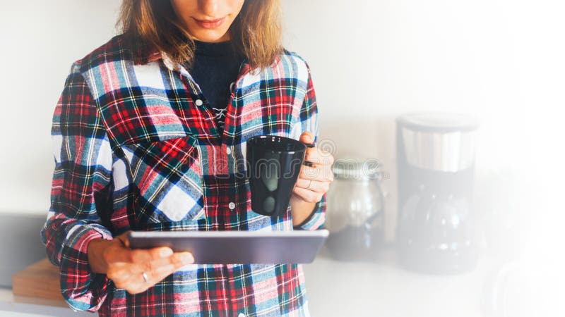 Hipster girl using tablet technology and drink coffee in kitchen, girl person holding computer on background interior cuisine, female hands texting message on relax holiday, templates gadget, blur lifestyle. Hipster girl using tablet technology and drink coffee in kitchen, girl person holding computer on background interior cuisine, female hands texting message on relax holiday, templates gadget, blur lifestyle