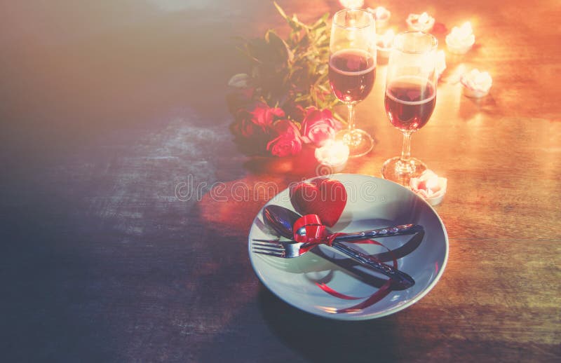 用红心在板材和夫妇香槟的叉子匙子装饰的华伦泰晚餐浪漫爱概念浪漫桌设置