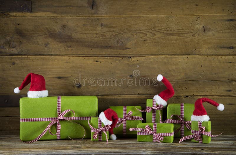 Christmas presents in apple green decorated with red santa hats on wooden rustic background. Idea for a gift certificate. Christmas presents in apple green decorated with red santa hats on wooden rustic background. Idea for a gift certificate.