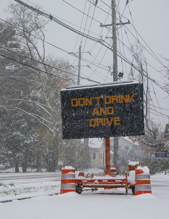 Electric road traffic mobile sign by the side of a snow covered road with snow falling that says, Don`t Drink and Drive. Electric road traffic mobile sign by the side of a snow covered road with snow falling that says, Don`t Drink and Drive