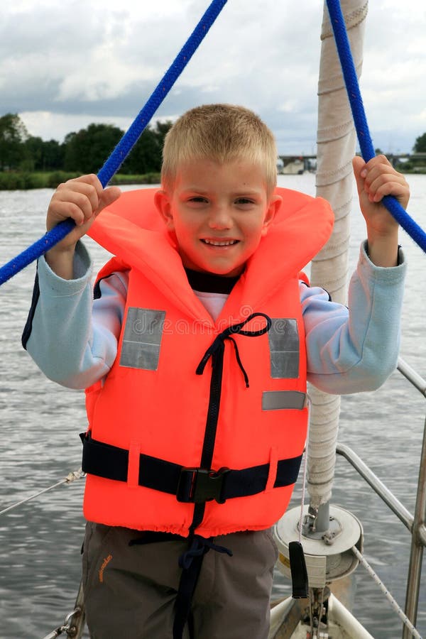 Boy in the life jacket on the yacht. He is pulling sheets (ropes). Sailing. Boy in the life jacket on the yacht. He is pulling sheets (ropes). Sailing.