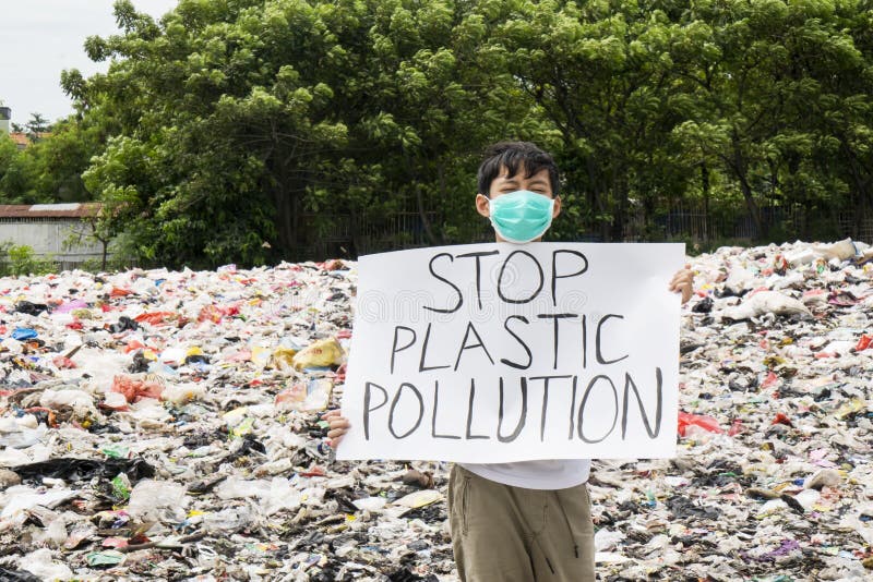 JAKARTA - Indonesia. May 27, 2019: Male teenager showing a text of stop plastic pollution in a paper and standing in the landfill. JAKARTA - Indonesia. May 27, 2019: Male teenager showing a text of stop plastic pollution in a paper and standing in the landfill