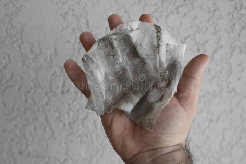 dirt, hairs and grey dust on wet wipes in male hand.  on white wall background. dirt, hairs and grey dust on wet wipes in male hand.  on white wall background.