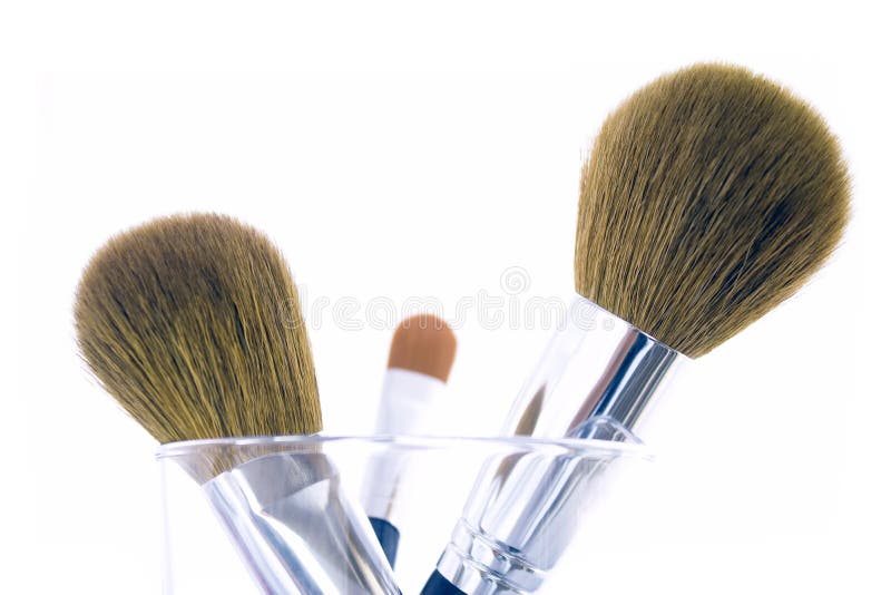 Set of three makeup brushes for face powder, concealer and eye shadow, in a glass. Isolated on white background. Set of three makeup brushes for face powder, concealer and eye shadow, in a glass. Isolated on white background.