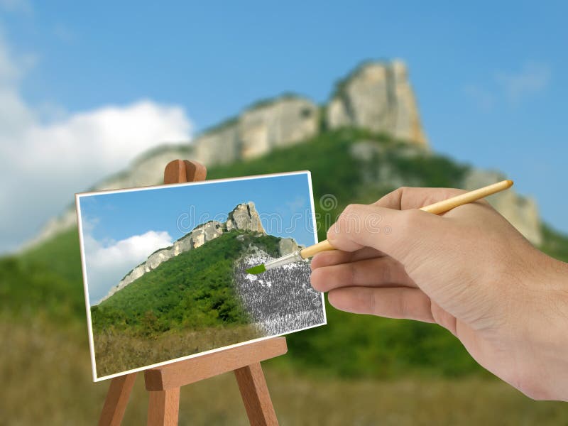 Hand with brush, mountain scene on paper. Hand with brush, mountain scene on paper