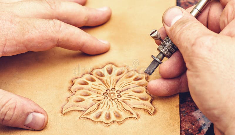 Leather artisan craftsman drawing an ornament on material. Workshop laboratory with instruments. View from top, green table. Leather artisan craftsman drawing an ornament on material. Workshop laboratory with instruments. View from top, green table