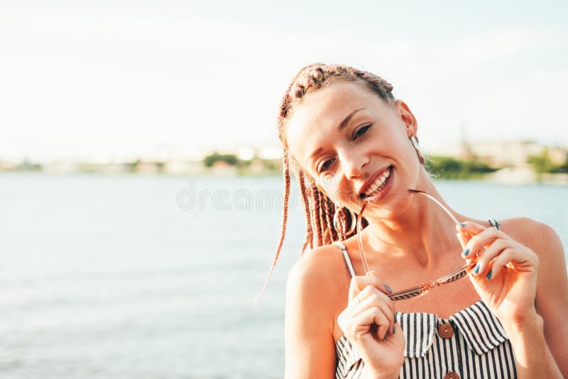 画象愉快的无忧无虑的年轻女人的关闭有在太阳镜的非洲辫子的享有在海滩的生活,暑假时间 库存照片 画象愉快的无忧无虑的年轻女人的关闭有在太阳镜的非洲辫子的享有在海滩的生活,暑假时间 库存照片