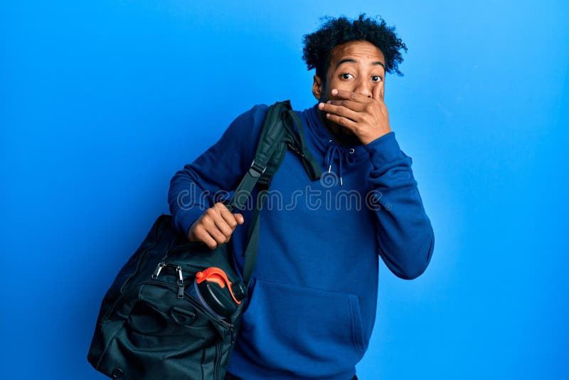 留着胡子的非洲裔年轻男子手牵健身袋，嘴巴被吓得一跳 库存照片