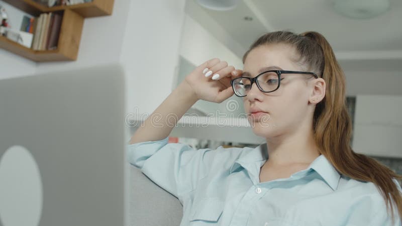 疲乏的十几岁的女孩学生在膝上型计算机在家键入，为检查或家庭作业做准备