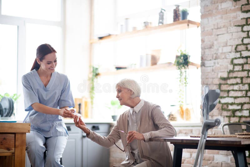 Woman taking pills. Grey-haired aged women taking pills from smiling young nurse. Woman taking pills. Grey-haired aged women taking pills from smiling young nurse