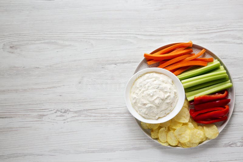 Homemade Caramelized Onion Dip with Potato Chips, Celery, Pepper and Carrot on a white wooden background, top view. Flat lay, overhead, from above. Homemade Caramelized Onion Dip with Potato Chips, Celery, Pepper and Carrot on a white wooden background, top view. Flat lay, overhead, from above.