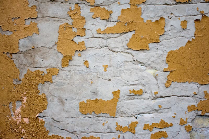 白砖墙，黄色旧石膏，在外面的天气条件下坍塌 库存图片