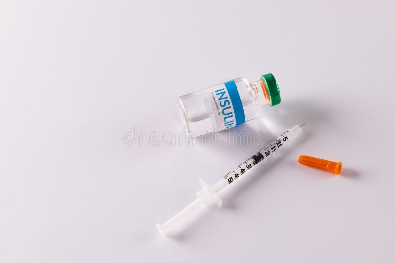 Insulin vial and uncapped syringe on white background with copy space. Blood sugar, diabetes and health awareness. Insulin vial and uncapped syringe on white background with copy space. Blood sugar, diabetes and health awareness.