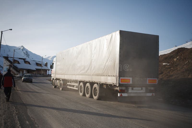 White refrigerated truck on winter road on background of the mountains. White refrigerated truck on winter road on background of the mountains.