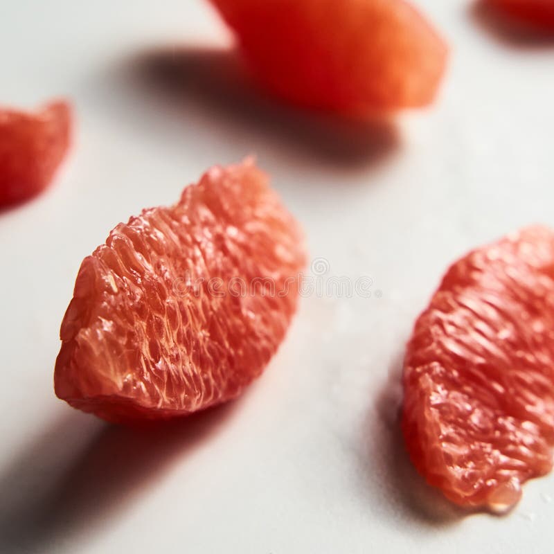 Close up of peeled and sliced, divided grapefruit segments on the white marble countertop. Bright, hey-key photo. High quality photo. Close up of peeled and sliced, divided grapefruit segments on the white marble countertop. Bright, hey-key photo. High quality photo