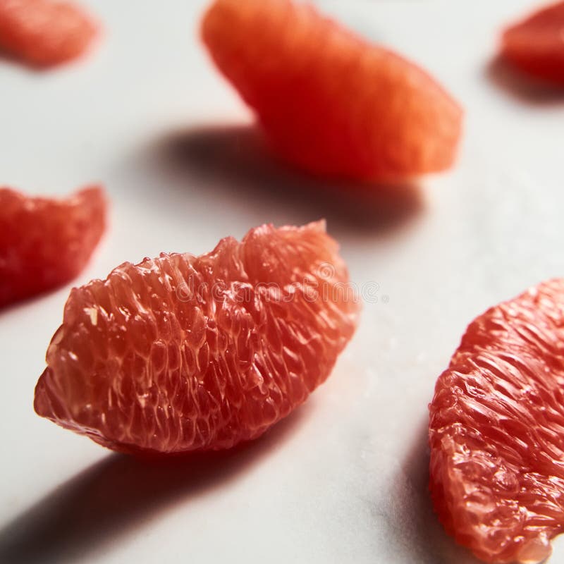Close up of peeled and sliced, divided grapefruit segments on the white marble countertop. Bright, hey-key photo. High quality photo. Close up of peeled and sliced, divided grapefruit segments on the white marble countertop. Bright, hey-key photo. High quality photo