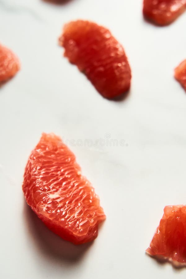 Close up of peeled and sliced, divided grapefruit segments on the white marble countertop. Bright, hey-key photo. High quality photo. Close up of peeled and sliced, divided grapefruit segments on the white marble countertop. Bright, hey-key photo. High quality photo