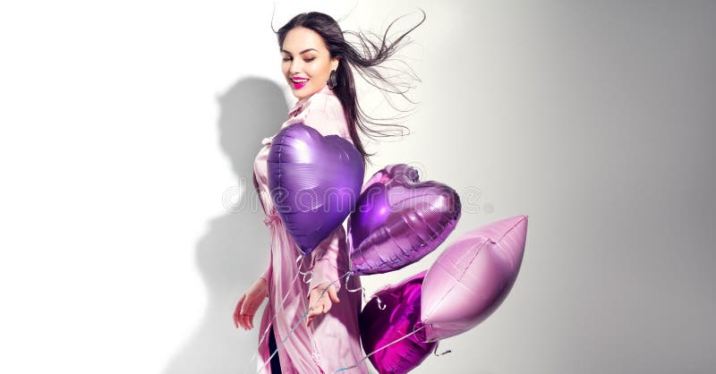白色背景中,情人节美女,带着彩色心气球笑着 美丽快乐的年轻女人 库存照片 白色背景中,情人节美女,带着彩色心气球笑着 美丽快乐的年轻女人 库存照片
