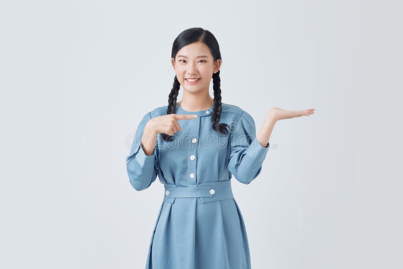 白色背景中的美丽女人，在她手上展示并指着一些令她吃惊的东西 库存照片