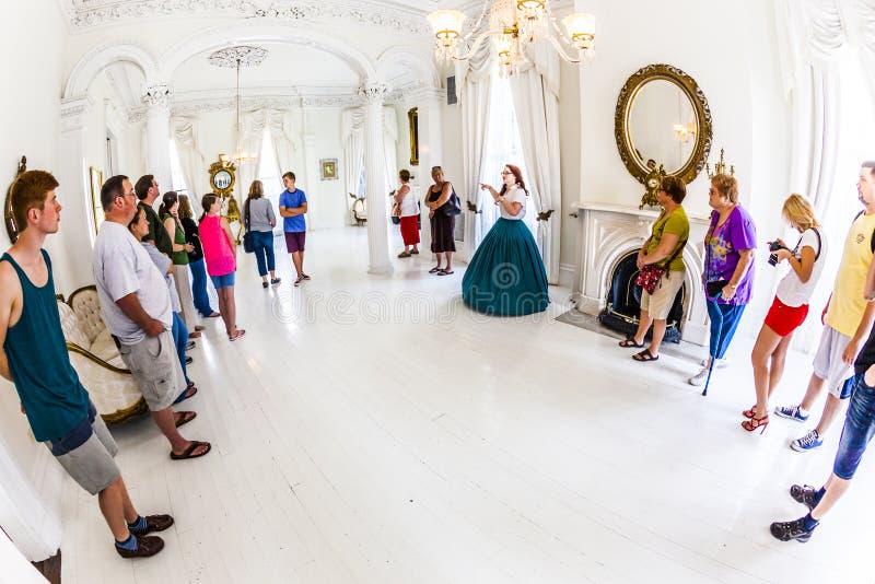 WHITE CASTLE, USA - JULY 14, 2013: Tourists in the White Ballroom in the Nottoway Plantation House during a guided tour. This room was painted completely white to show off the natural beauty of all of the women. Nottoway Plantation is famous for romantic weddings nowadays. WHITE CASTLE, USA - JULY 14, 2013: Tourists in the White Ballroom in the Nottoway Plantation House during a guided tour. This room was painted completely white to show off the natural beauty of all of the women. Nottoway Plantation is famous for romantic weddings nowadays.