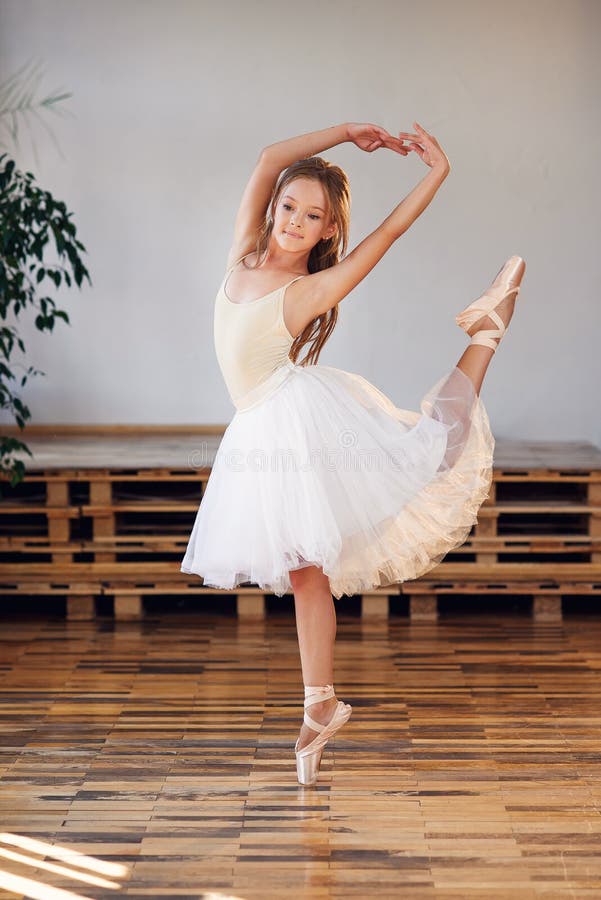 Young ballerina in white tutu practicing dance moves. Young girl in ballet dress at dance school. Young ballerina in white tutu practicing dance moves. Young girl in ballet dress at dance school.