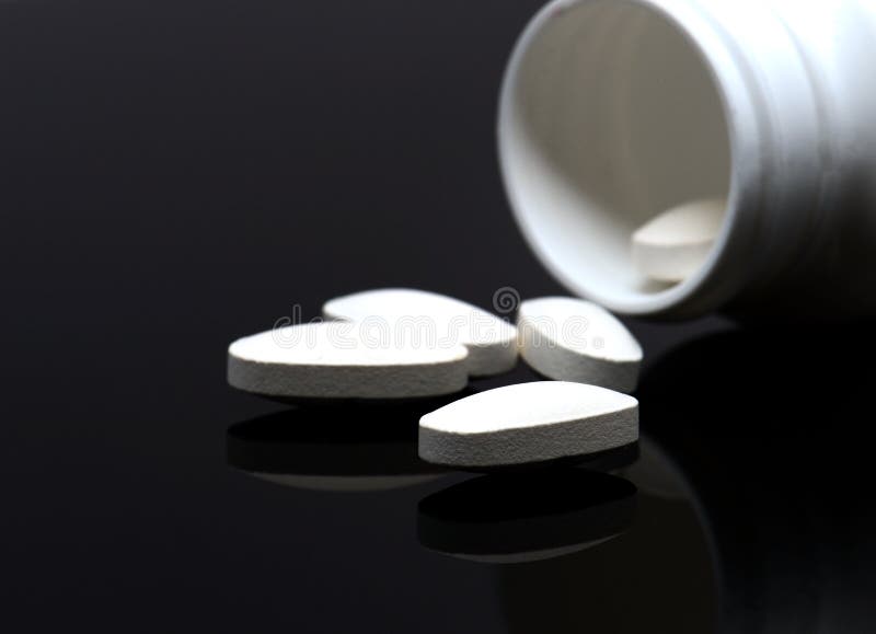 White pills and a bottle on black background. White pills and a bottle on black background