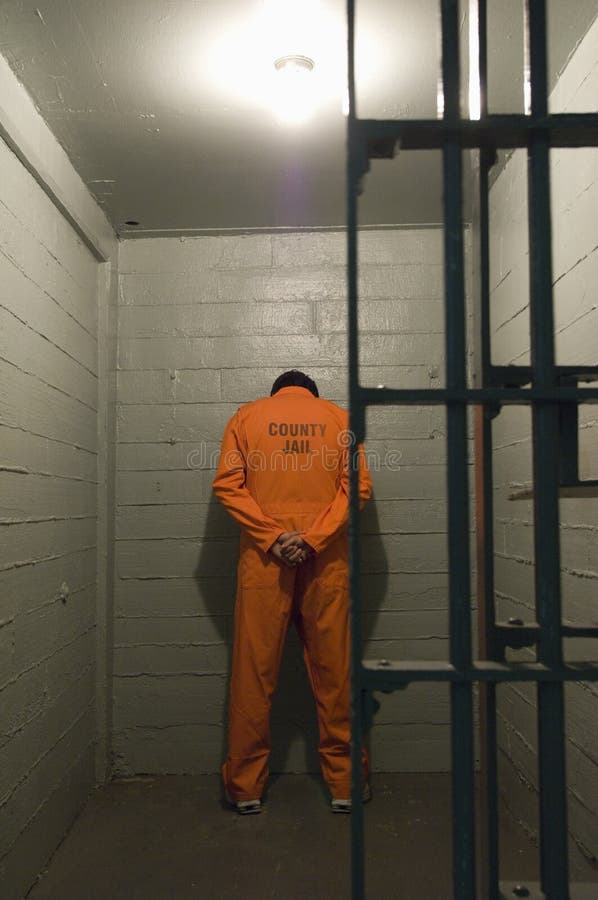 Prisoner standing against the wall in prison cell. Prisoner standing against the wall in prison cell