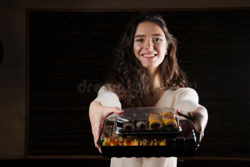 Sushi in box healthy food delivery online service. Girl holds 2 sushi sets in hands. Japanese cuisine: rolls, soy sauce, wasabi. Sushi in box healthy food delivery online service. Girl holds 2 sushi sets in hands. Japanese cuisine: rolls, soy sauce, wasabi