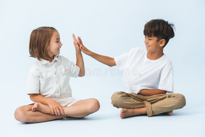 盘腿坐在地上，仰望双手的坚定的男孩女孩 免版税图库摄影