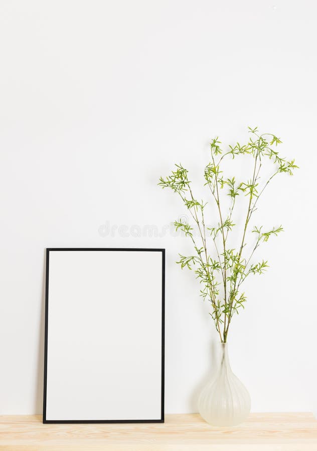 Black picture frame and spring tree branches in an elegant vase. Modern home decor. Black picture frame and spring tree branches in an elegant vase. Modern home decor.