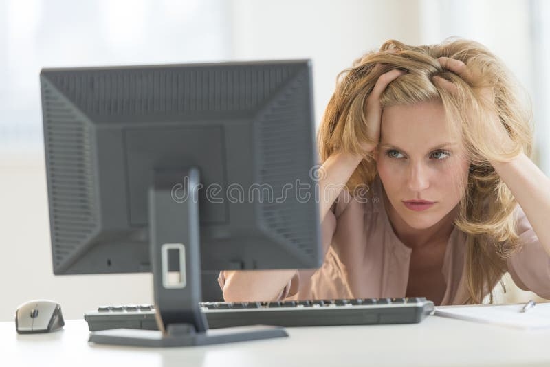 看台式计算机的沮丧的女实业家在办公室