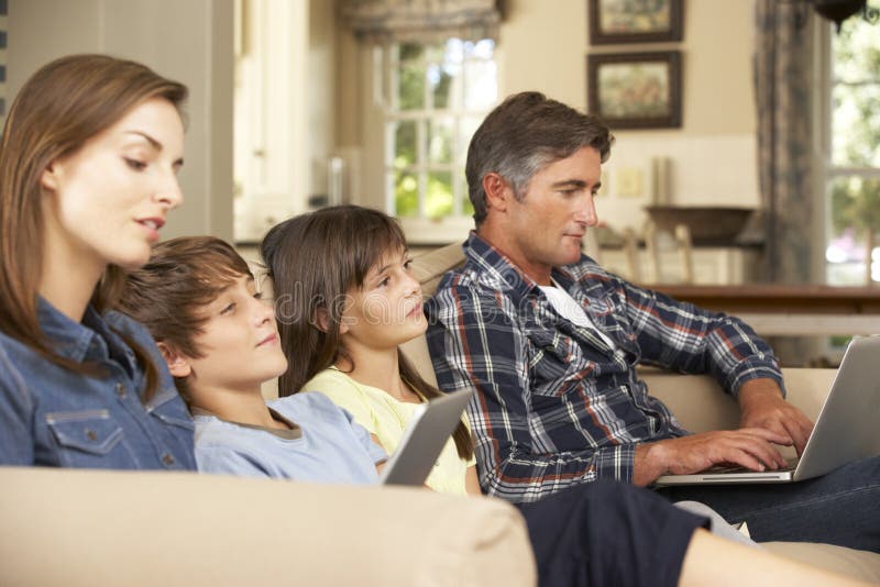 看电视的孩子，父母在家使用膝上型计算机和片剂计算机