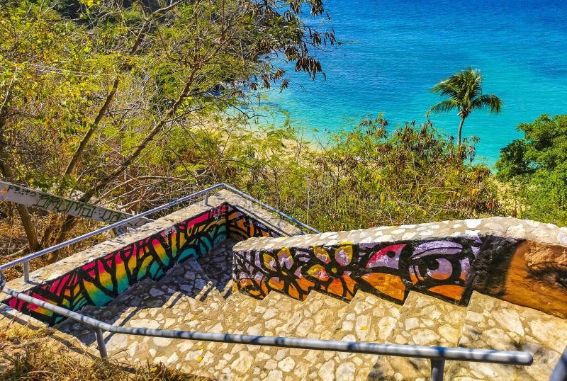 Puerto Escondido Oaxaca Mexico 01. February 2023 Stone stairs steps trail with paintings art down to the beach sand turquoise blue water rocks cliffs boulders palm trees big surfer waves on Playa Carrizalillo in Mexico. Puerto Escondido Oaxaca Mexico 01. February 2023 Stone stairs steps trail with paintings art down to the beach sand turquoise blue water rocks cliffs boulders palm trees big surfer waves on Playa Carrizalillo in Mexico