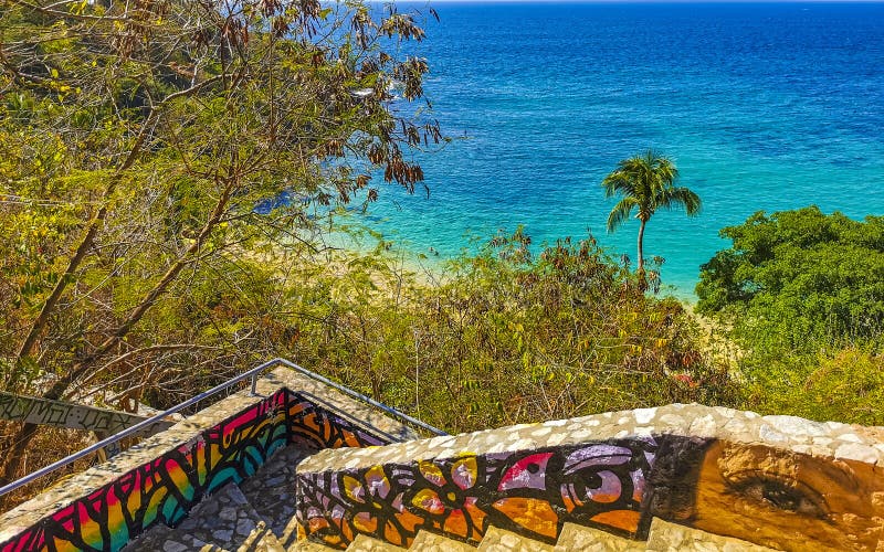 Puerto Escondido Oaxaca Mexico 01. February 2023 Stone stairs steps trail with paintings art down to the beach sand turquoise blue water rocks cliffs boulders palm trees big surfer waves on Playa Carrizalillo in Mexico. Puerto Escondido Oaxaca Mexico 01. February 2023 Stone stairs steps trail with paintings art down to the beach sand turquoise blue water rocks cliffs boulders palm trees big surfer waves on Playa Carrizalillo in Mexico