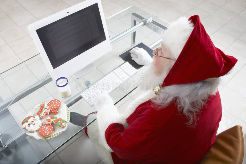 High angle view of Santa Claus working on computer. High angle view of Santa Claus working on computer