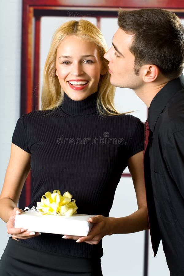 Young attractive happy smiling business people or couple with gift. Young attractive happy smiling business people or couple with gift