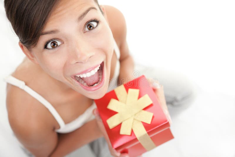 Happy excited woman holding gift / present. Cute surprised mixed Asian Chinese / Caucasian female model. Happy excited woman holding gift / present. Cute surprised mixed Asian Chinese / Caucasian female model.