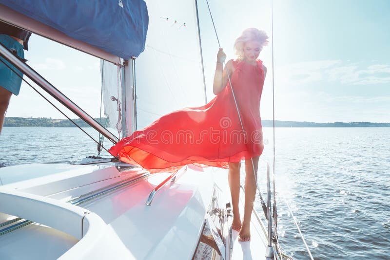 礼服的美丽的年轻性感的深色的女孩和构成、夏天旅行在一条游艇有白色风帆的在海或海洋海湾的 免版税图库摄影 礼服的美丽的年轻性感的深色的女孩和构成、夏天旅行在一条游艇有白色风帆的在海或海洋海湾的 免版税图库摄影