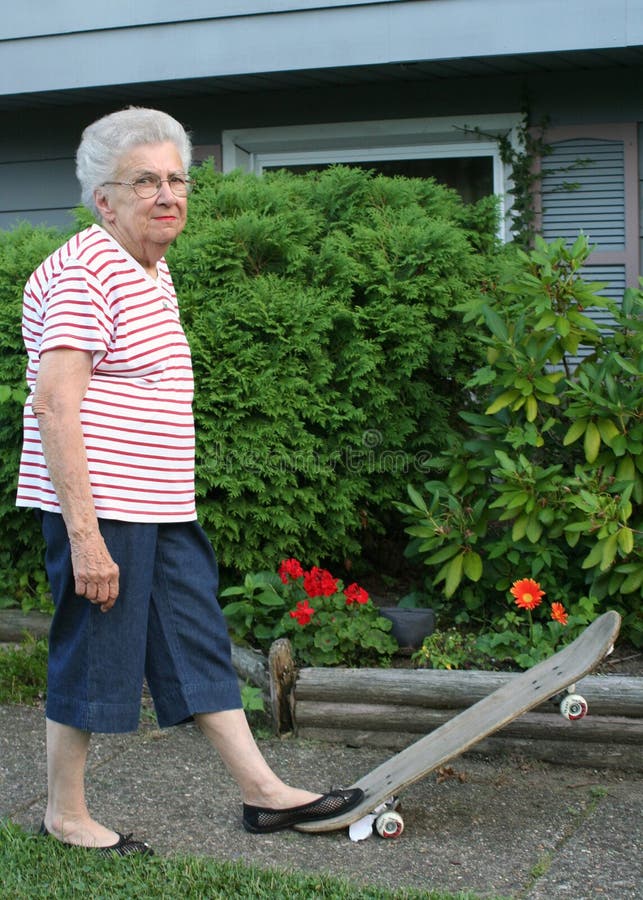 Senior citizen woman standing with one foot on tilted skateboard. Senior citizen woman standing with one foot on tilted skateboard.