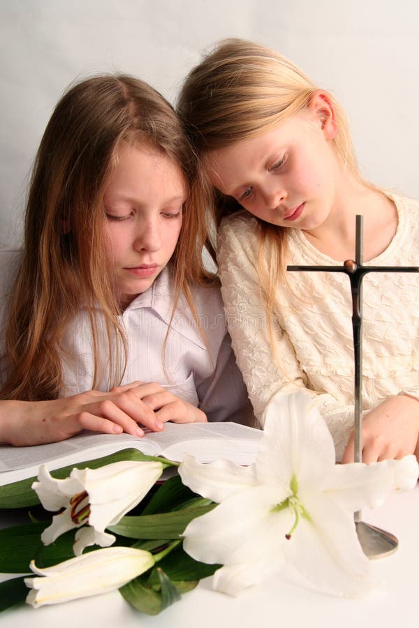 Two sister reading holy bible together and easter lilies lying on the table. Two sister reading holy bible together and easter lilies lying on the table.