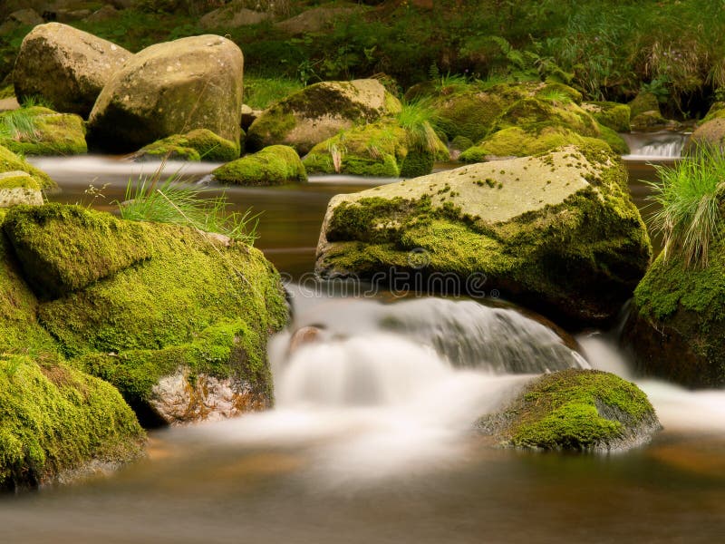 Blurred rapids of autumn mountain river, big mossy boulders obstruct water in motion, bubbles create milky foam. Blurred rapids of autumn mountain river, big mossy boulders obstruct water in motion, bubbles create milky foam.