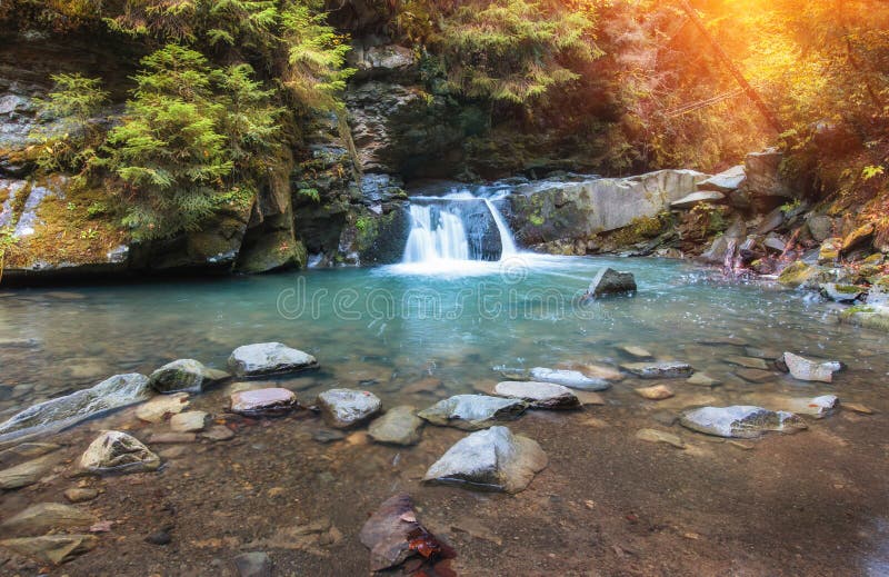 Autumn landscape. Beautiful fall scene on a clear mountain river with small waterfall and rapids, gravel with with colorful rocky bottom and fallen leaves at sunlight. Autumn landscape. Beautiful fall scene on a clear mountain river with small waterfall and rapids, gravel with with colorful rocky bottom and fallen leaves at sunlight.